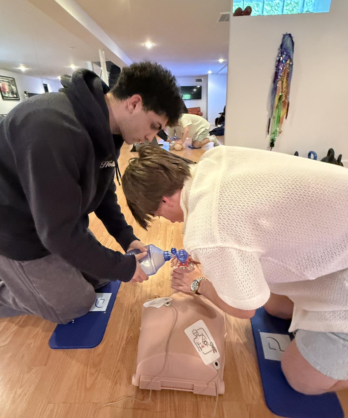 Instructor coaching a student through bandaging during a first aid class